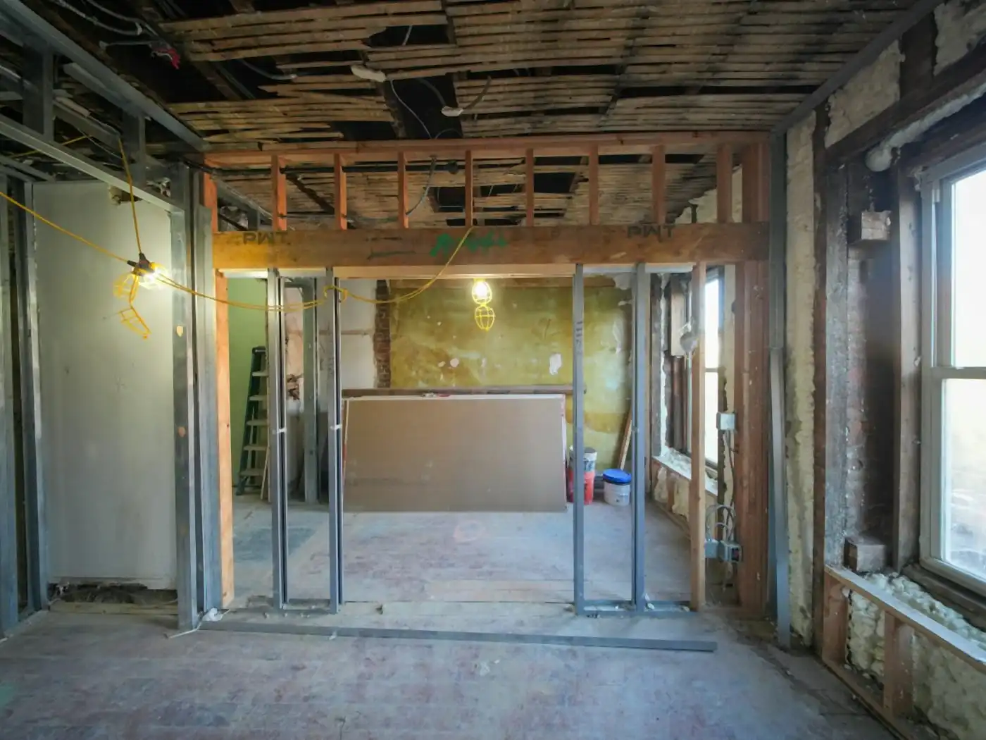 Home interior under renovation, with new wall framing and the ceiling opened up